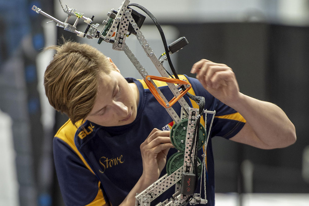 A young male robotics student adjusting his robot.