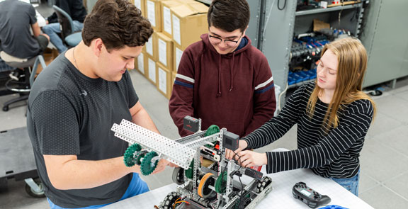 Three students building their VEX EDR robot.